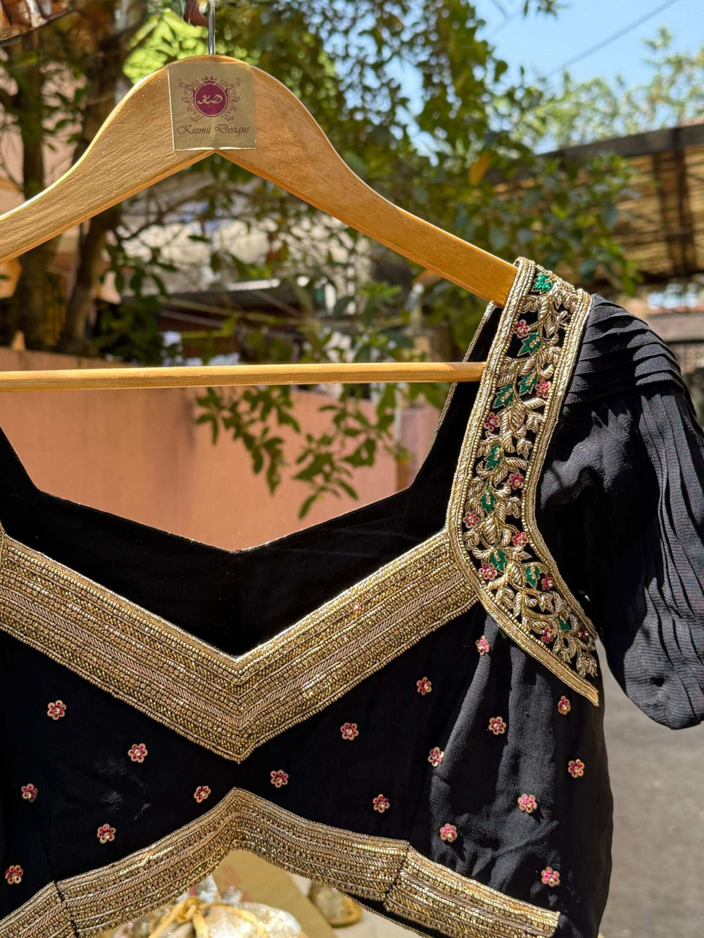 Small pink floral bootis scattered across the blouse body below the zari border