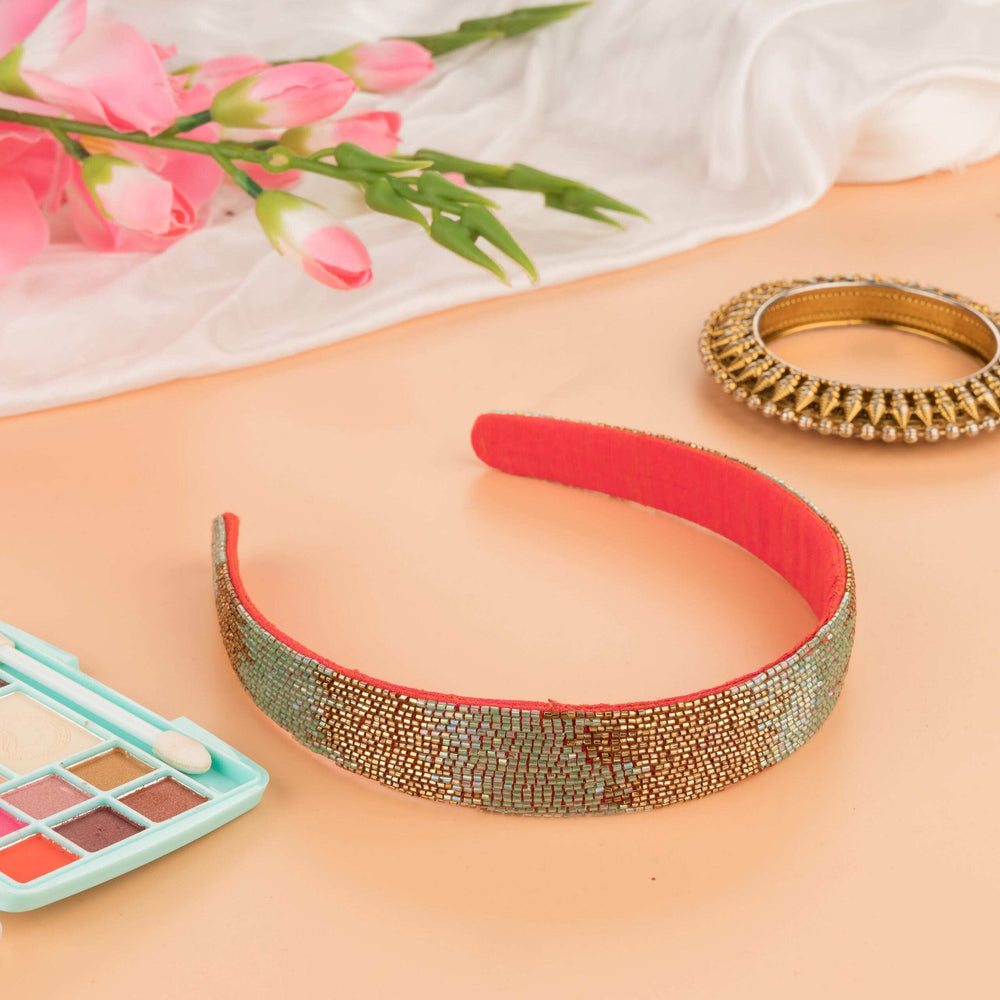 Beaded headband in gold and pale silver on a coral band, with makeup palette and tulips