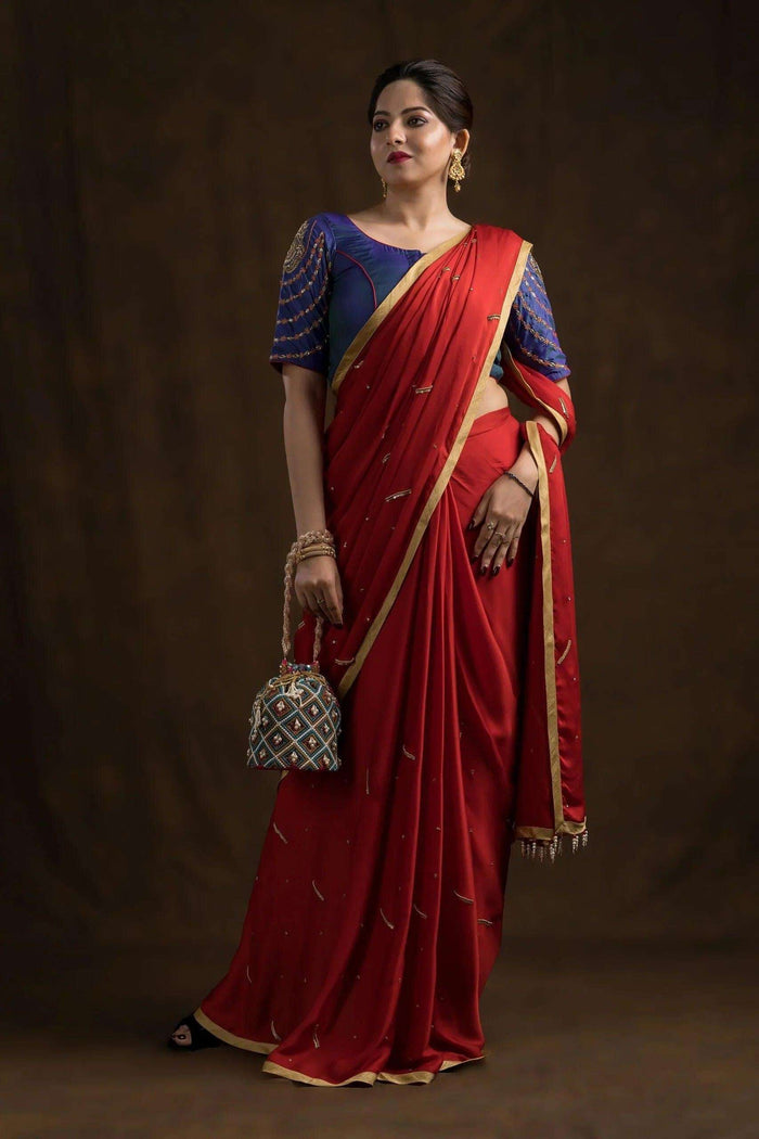 Full length shot of the red saree drape with the potli bag held in one hand