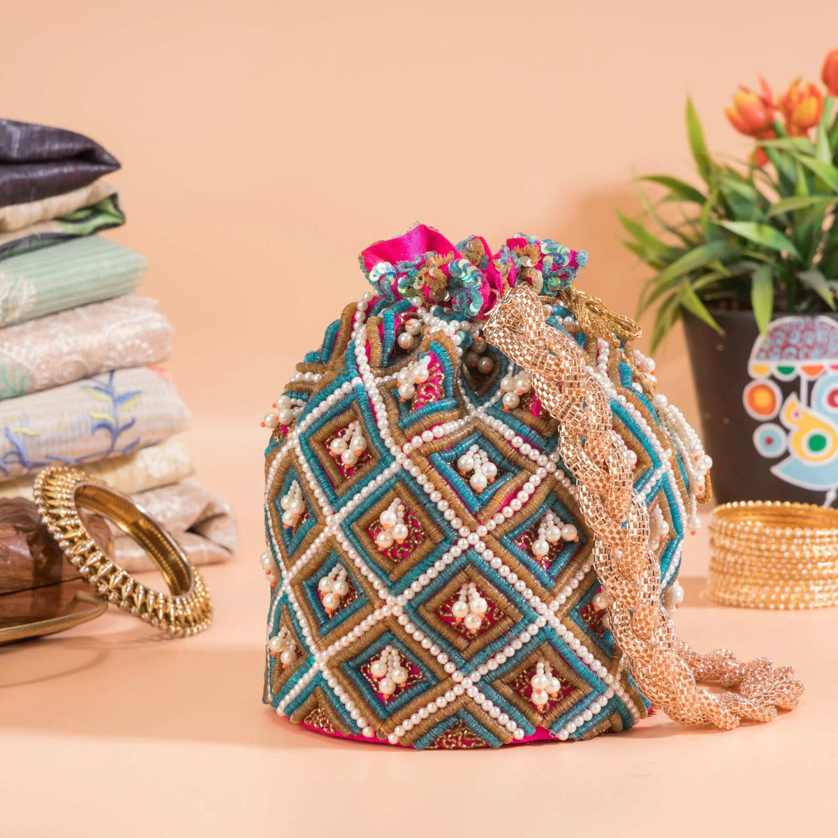 Bag seen from the side with pink drawstring gathers and bangles in the background