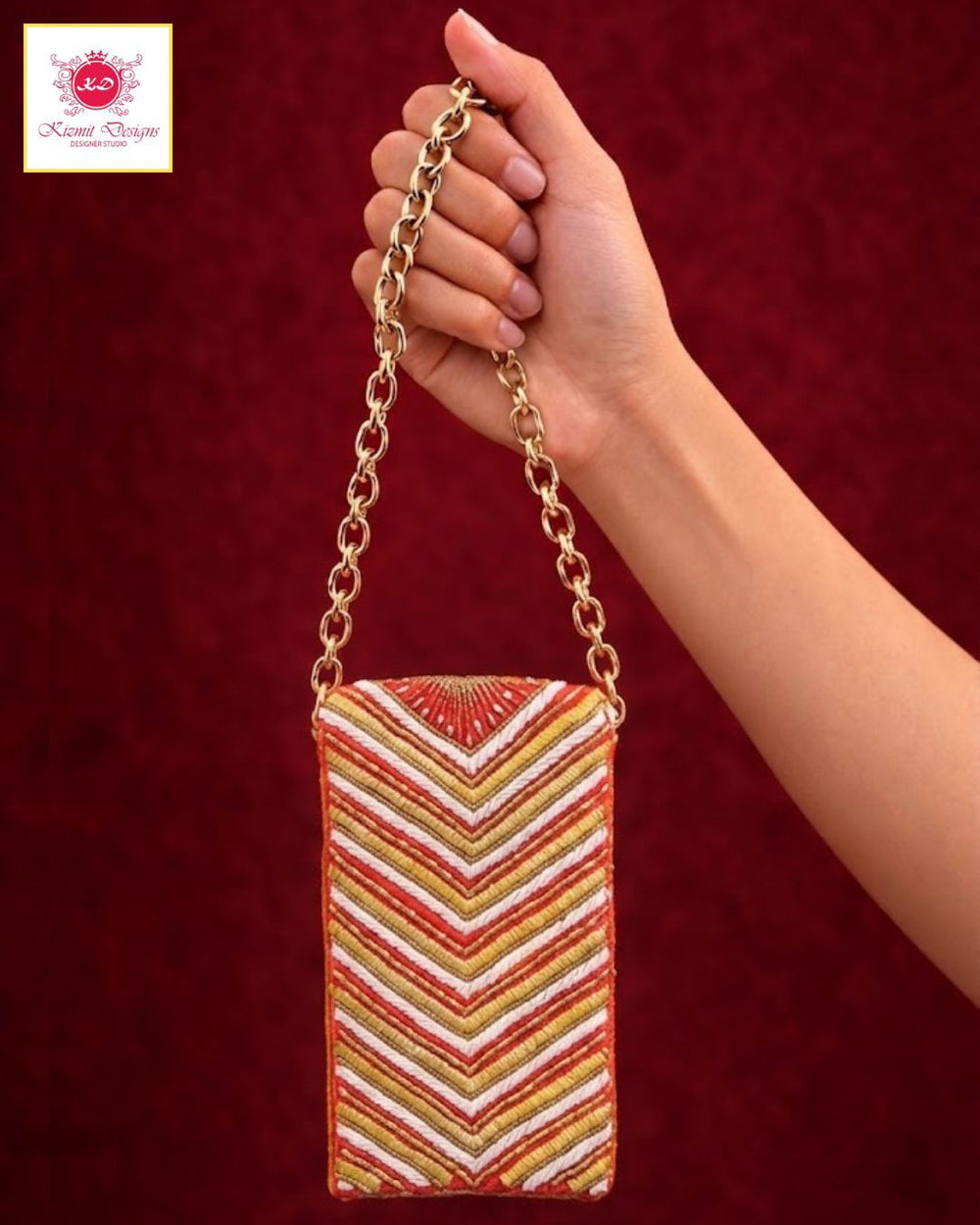 Hand holding a rectangular chain sling bag worked in red, white and gold chevron threadwork