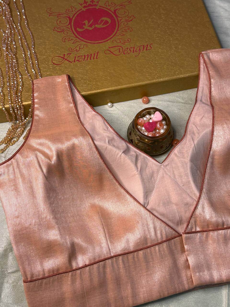 Sleeveless rose gold blouse, front V-neckline finished with fine piped edging