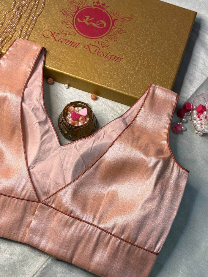 Angled view of the rose gold blouse showing the V-neck and side seam on pale cloth