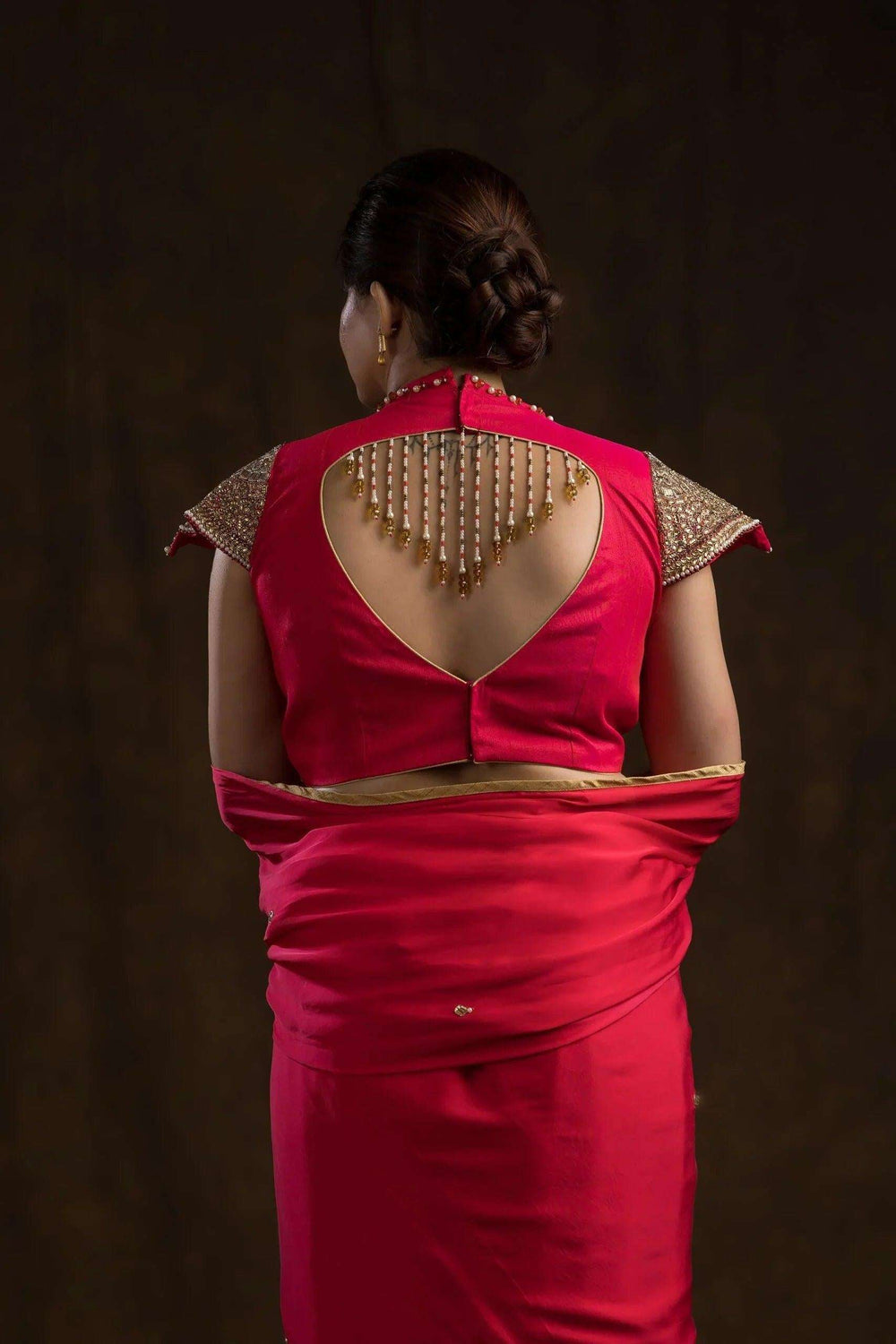 Back view with a deep cut-out and hanging pearl drop strings on the pink blouse
