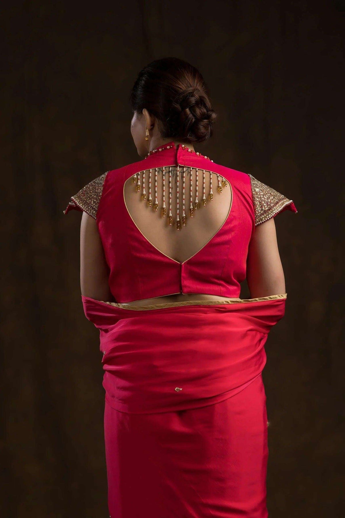 Back view with a deep cut-out and hanging pearl drop strings on the pink blouse