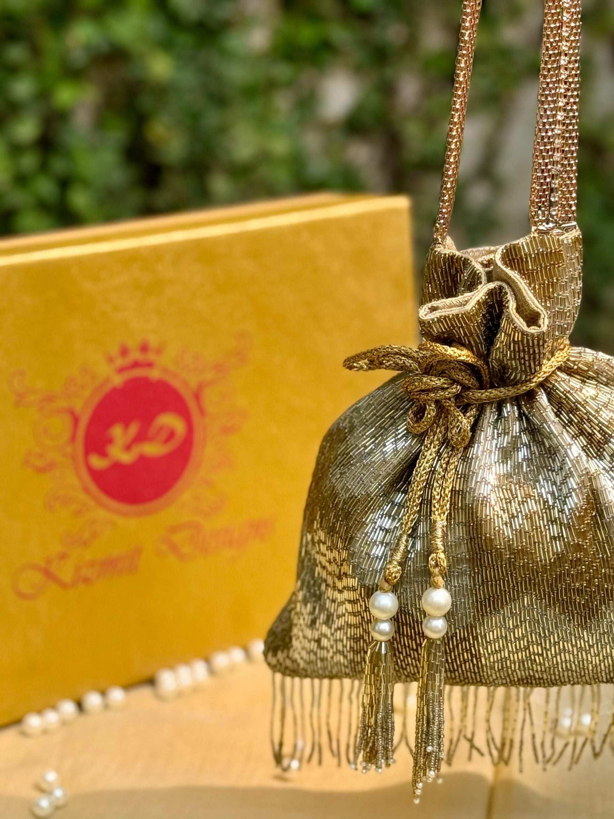 Close-up of the gold potli's drawstring knot, tassels and metallic chain handle